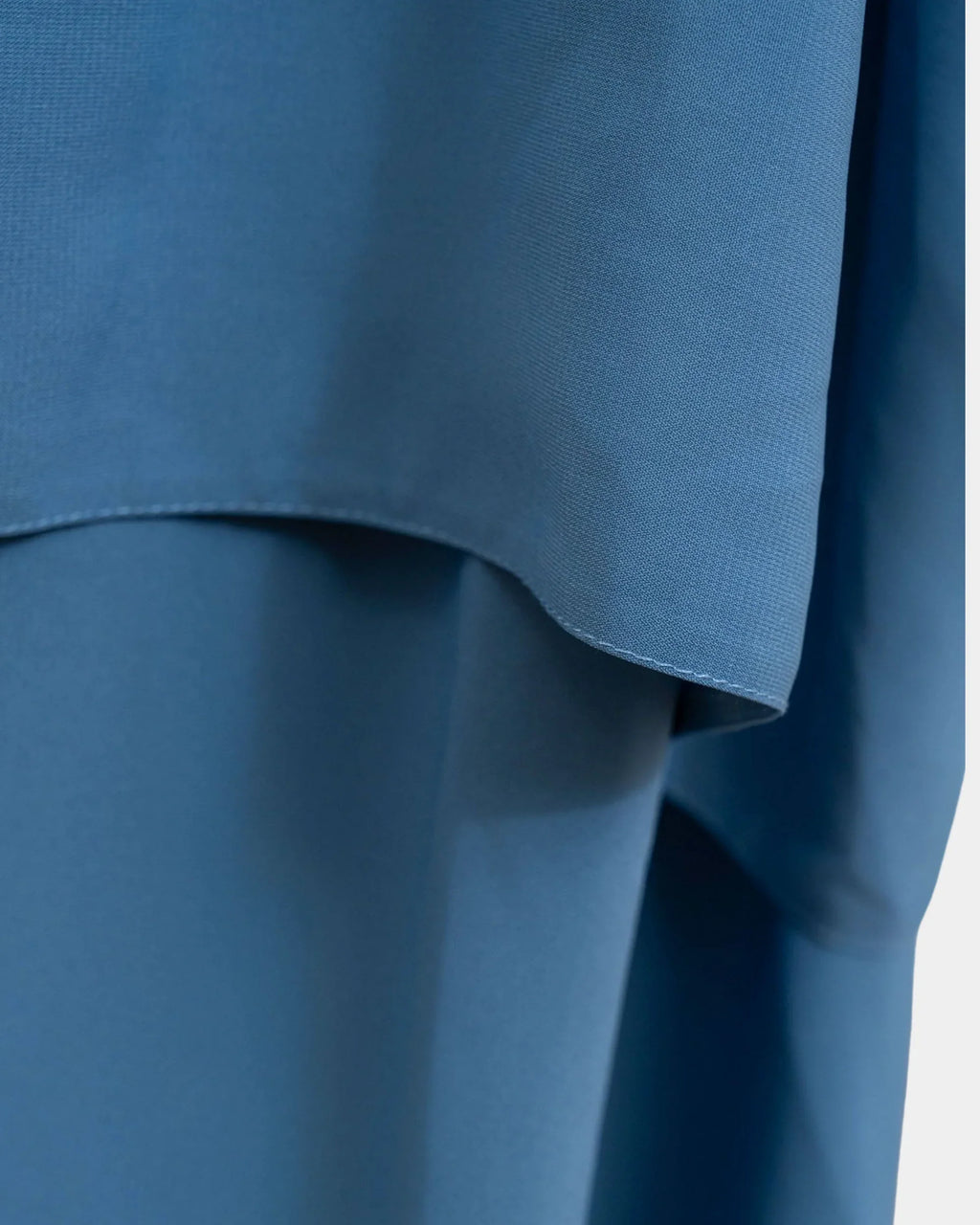 Ourlet du khimar bleu jean retombant sur la jupe assortie, finition surpiquée