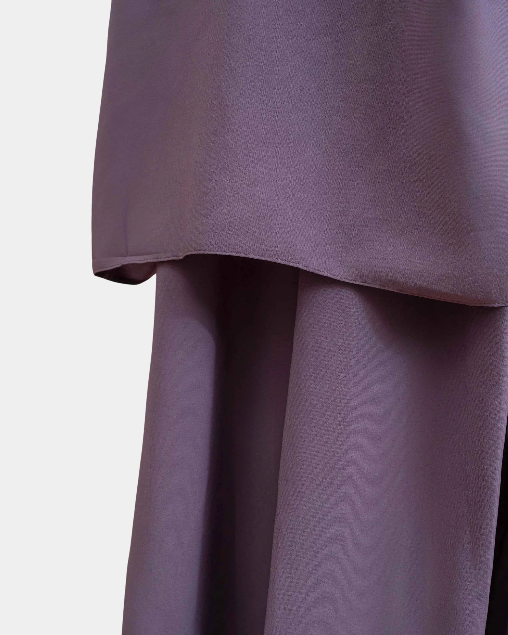 Ourlet du khimar lilas retombant sur la jupe assortie, finition surpiquée
