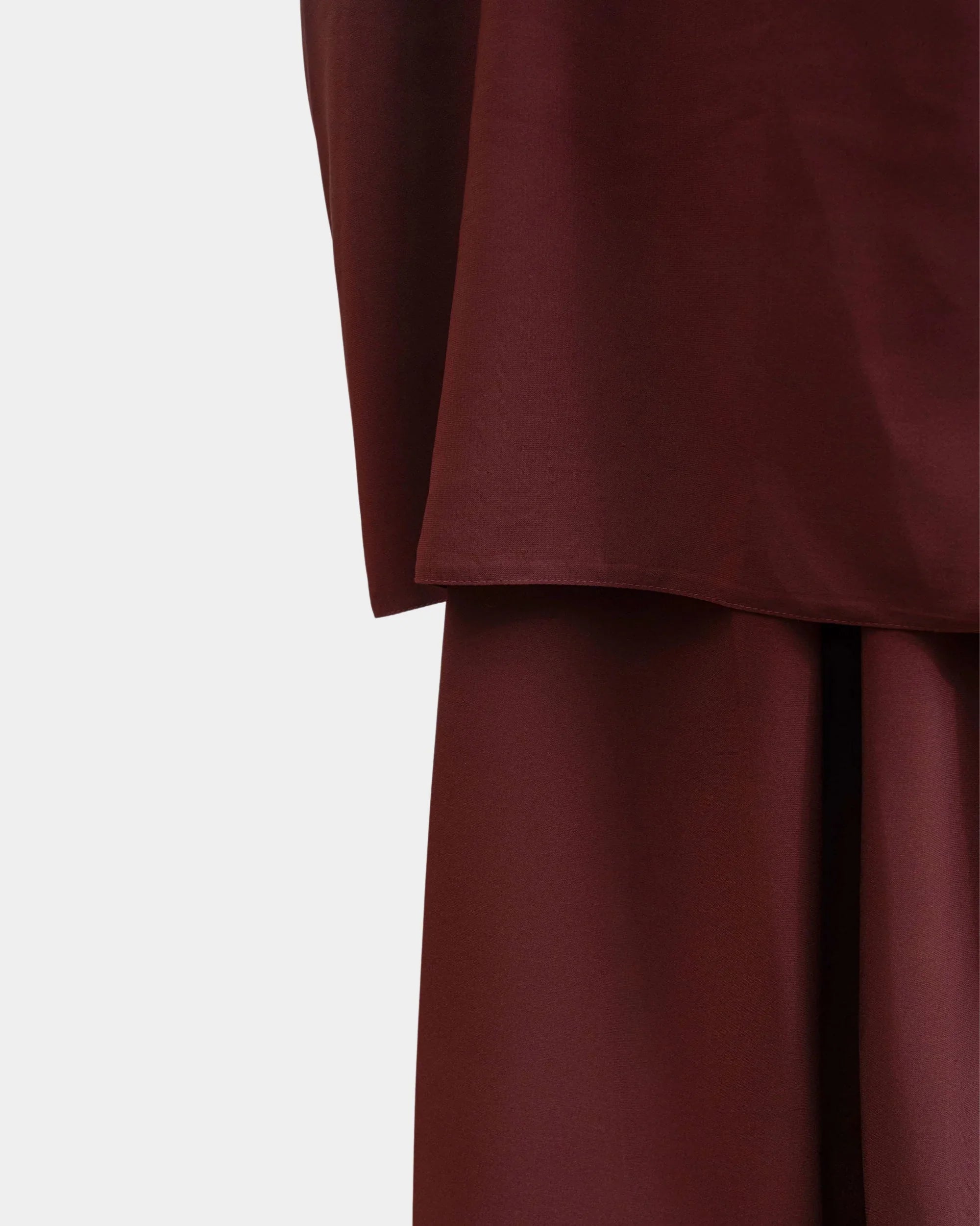 Ourlet du khimar rouille retombant sur la jupe assortie, finition surpiquée