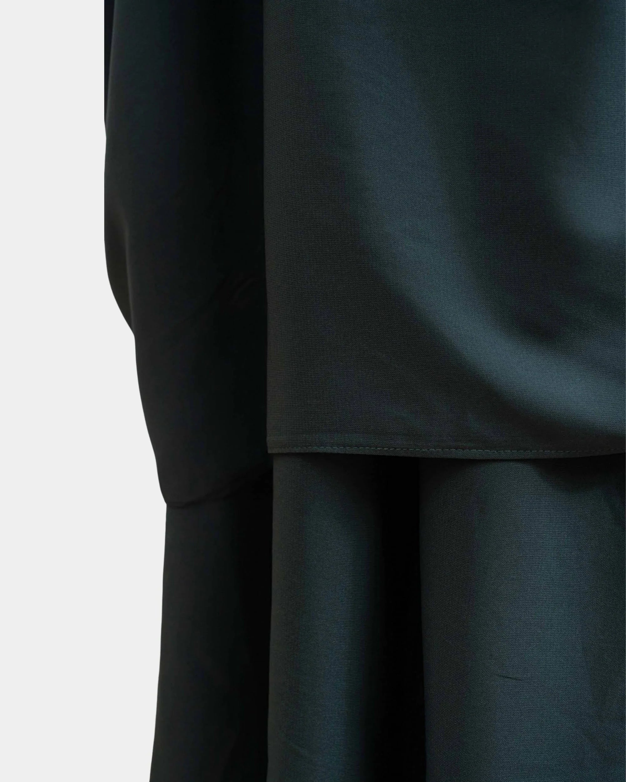 Ourlet du khimar vert kaki retombant sur la jupe assortie, finition surpiquée