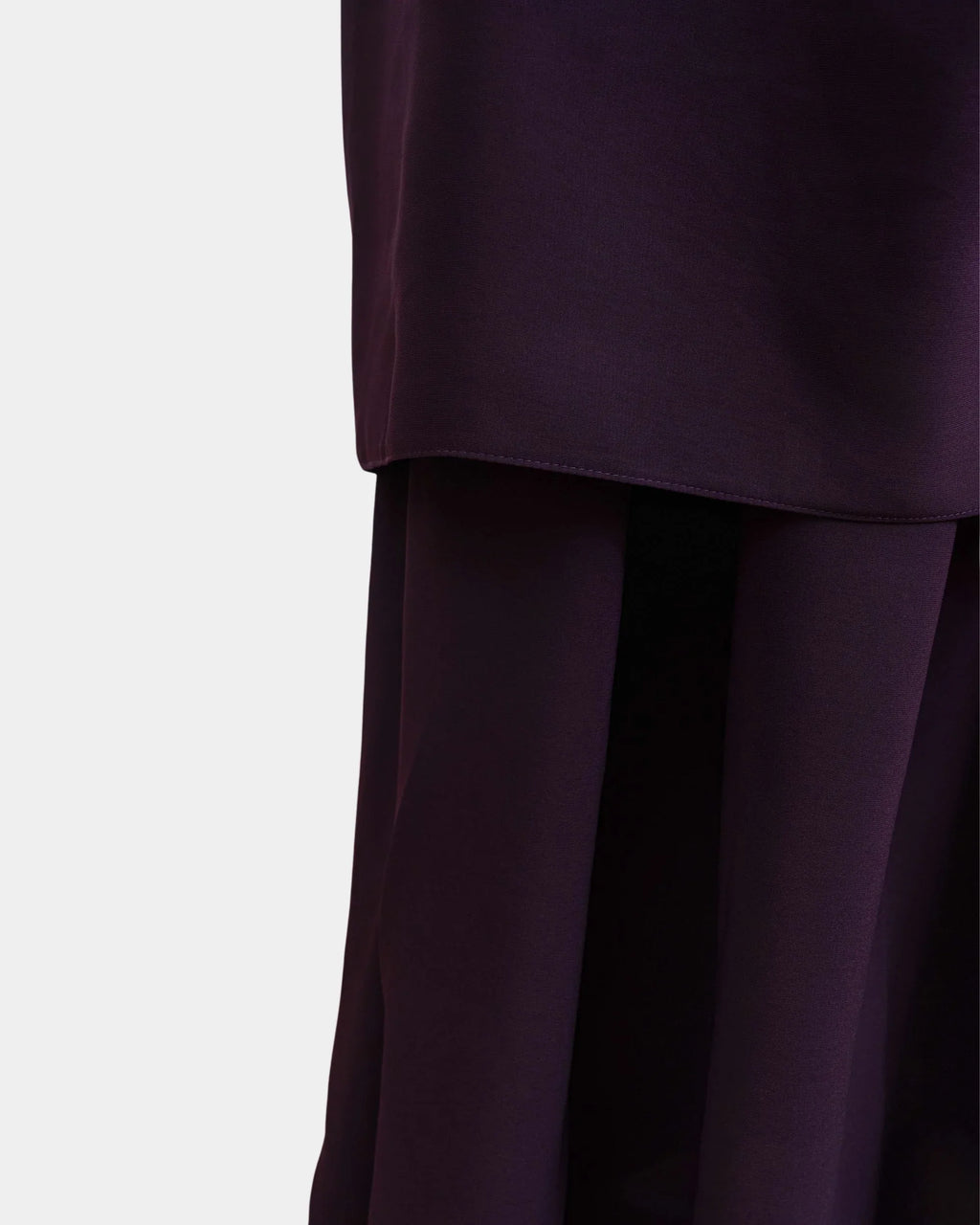 Ourlet du khimar violet framboise retombant sur la jupe assortie, finition surpiquée
