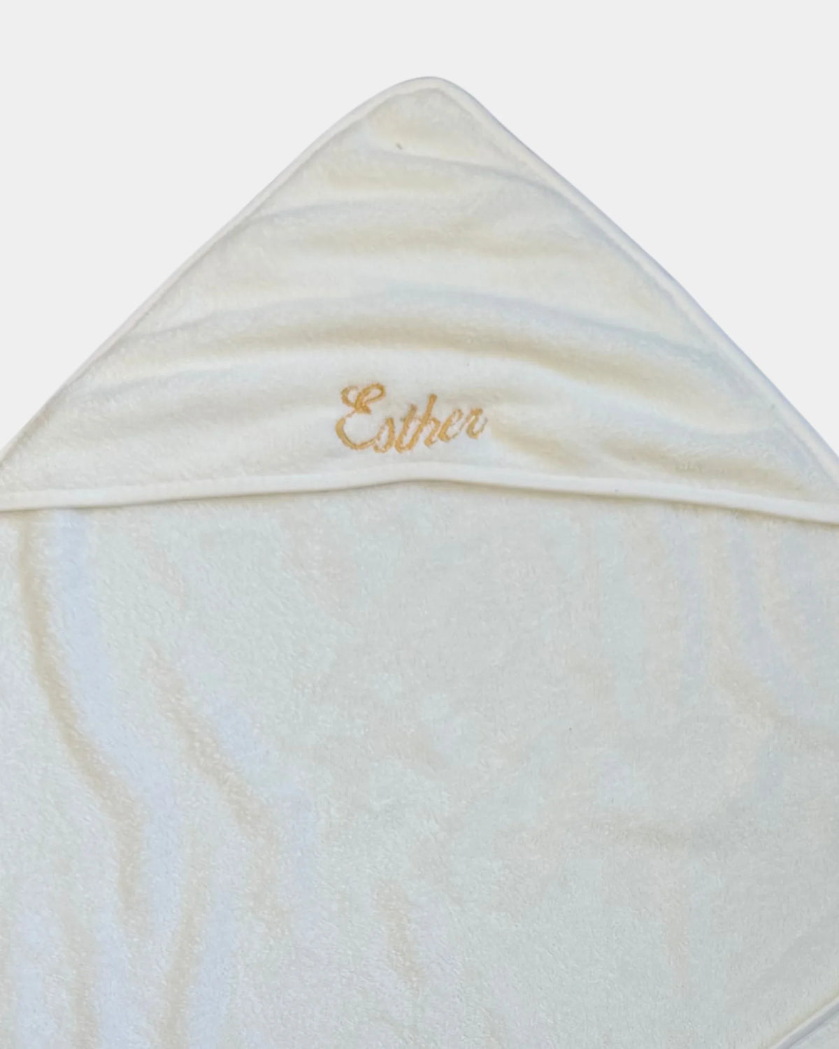 Détail de la broderie du prénom en fil doré sur la capuche de la serviette de bain bébé
